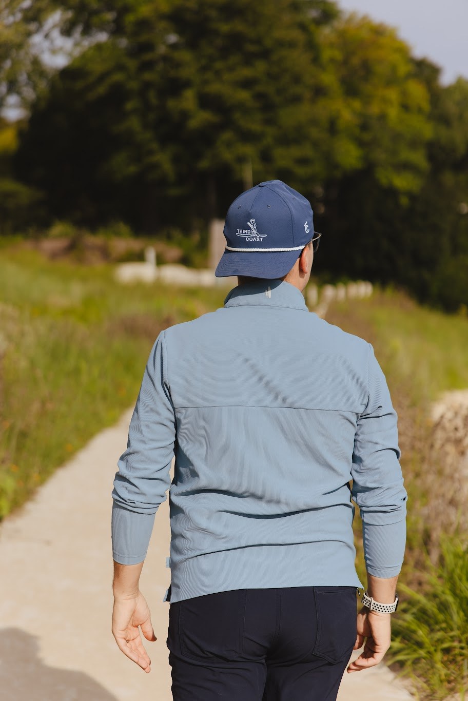 The Third Coast quarter-zip and paddleboarder rope cap on the path to the beach
